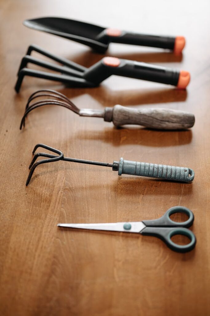 Flat lay of various garden tools on a wooden surface, perfect for home improvement and gardening themes.